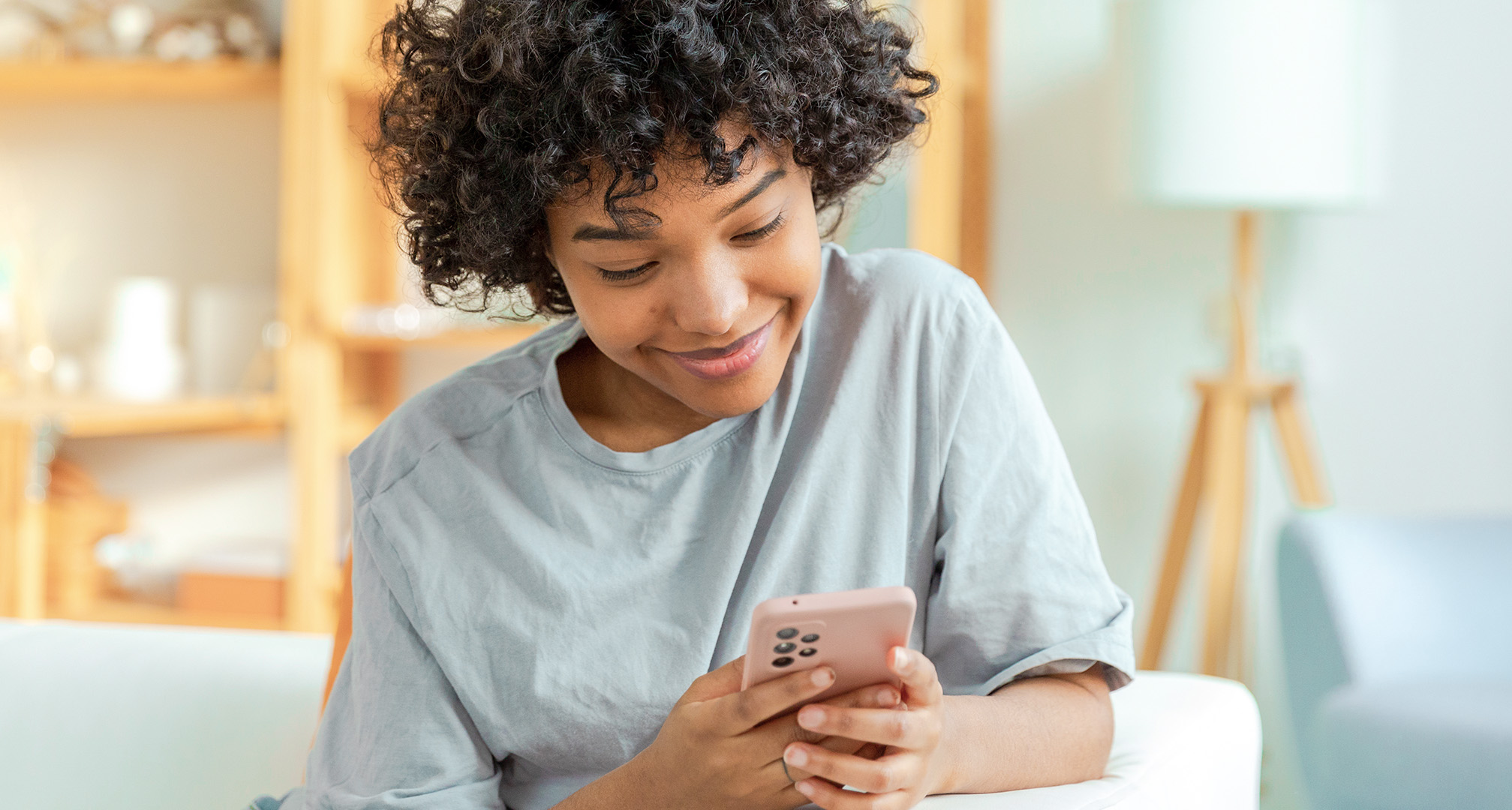 bližinska fotografija osebe, ki se smehlja in gleda v mobilni telefon